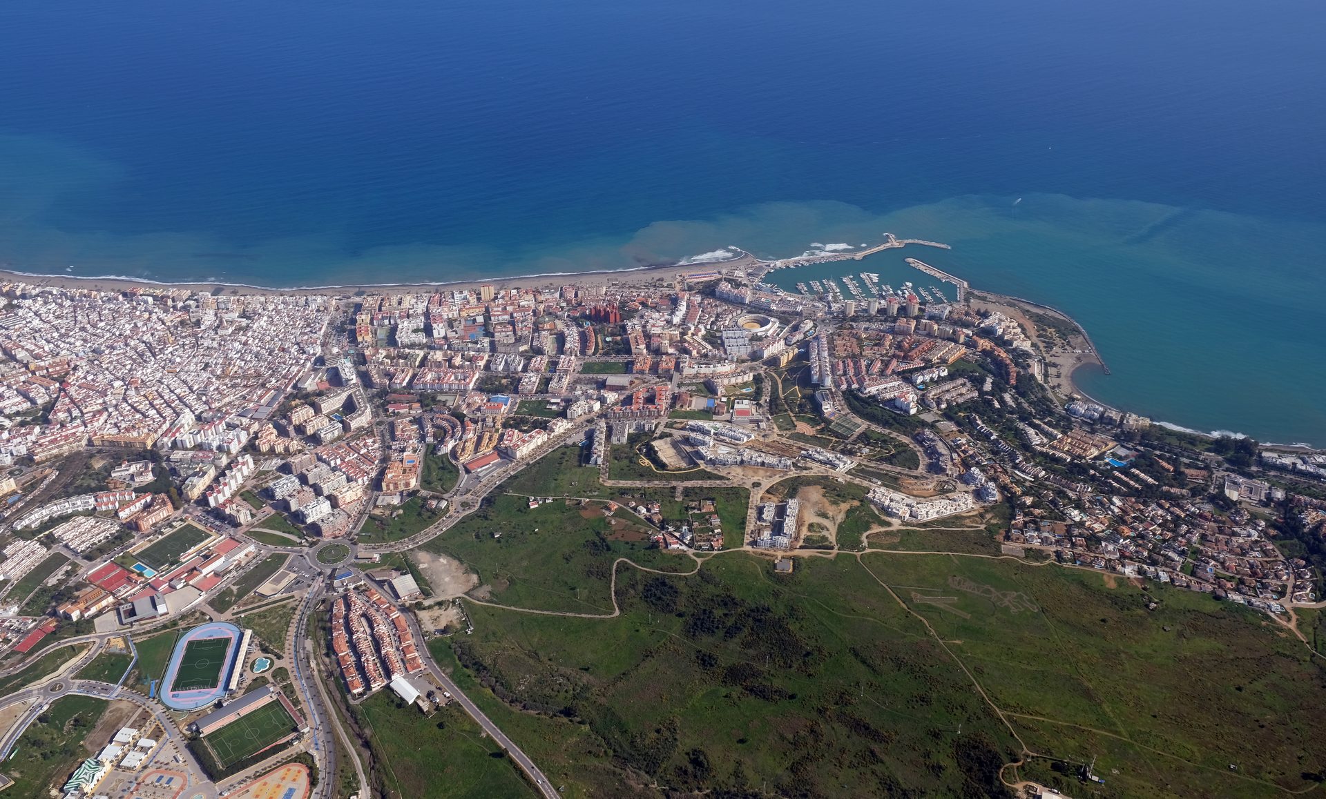 Aerial view of a coastal city with a mix of urban and green areas.