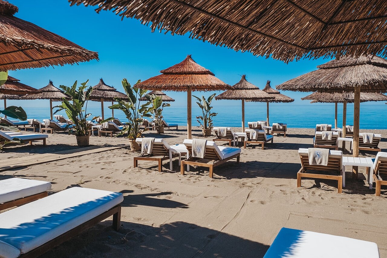 Strand van Estepona met ligbedden, rieten parasols en uitzicht op zee
